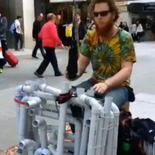 Músico de rua toca instrumento feito de canos