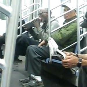 Homem limpa próprio sapato com a língua no metrô.